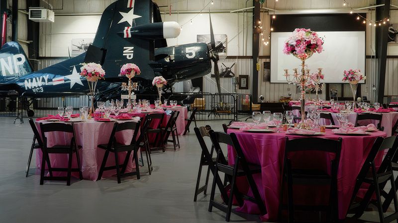 tables and chairs in hangar, airplane in background