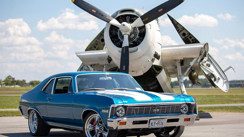 a blue mustang in front of an airplane