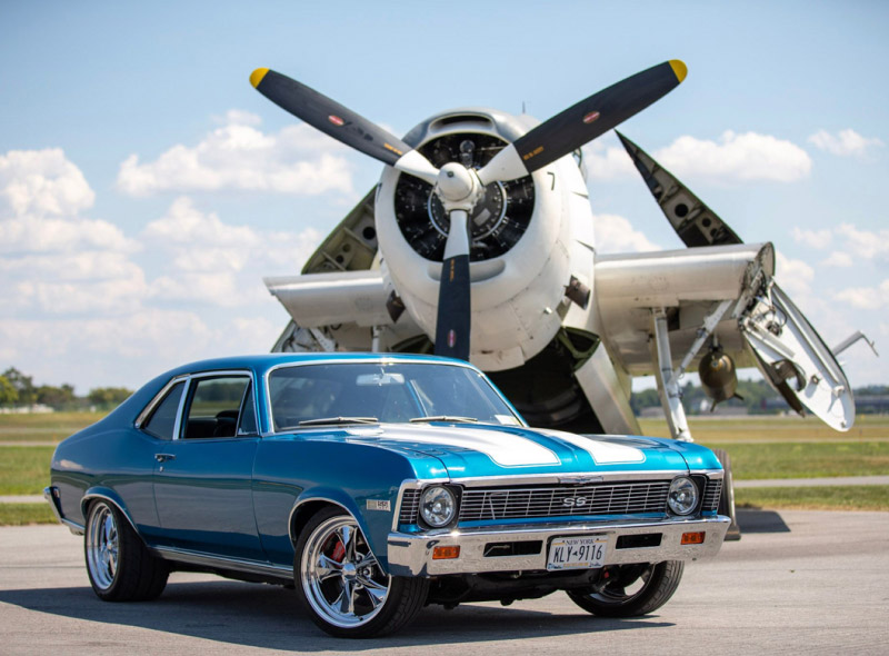 a blue mustang in front of an airplane