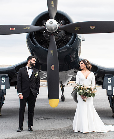 bride and groom standing in front of plane