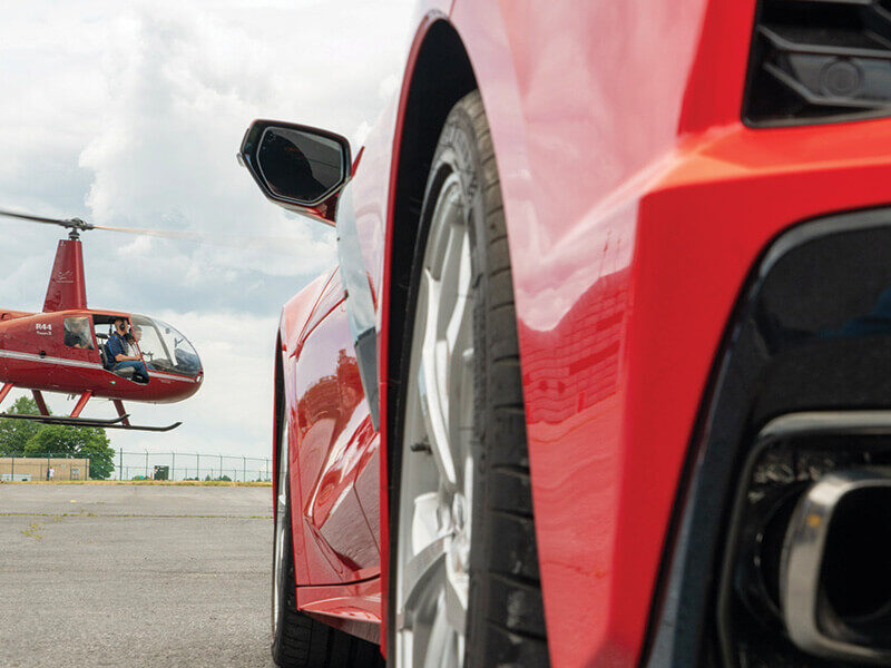 Red sports car with red helicopter in background